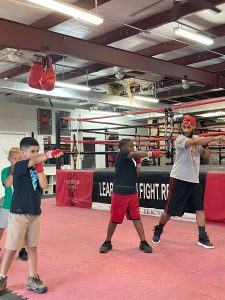 Children practicing boxing in a gym under an instructor's guidance.
